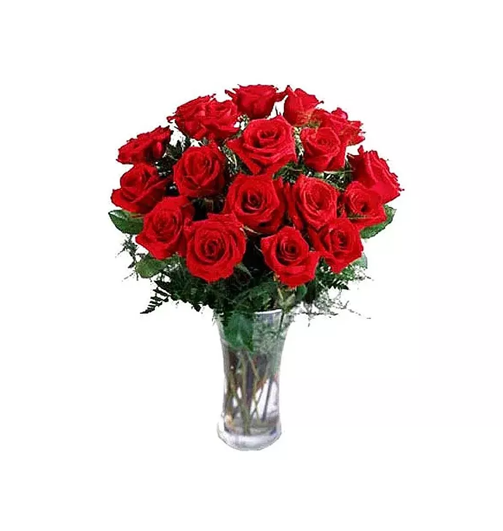 18 Roses artfully arranged in a glass vase with greens